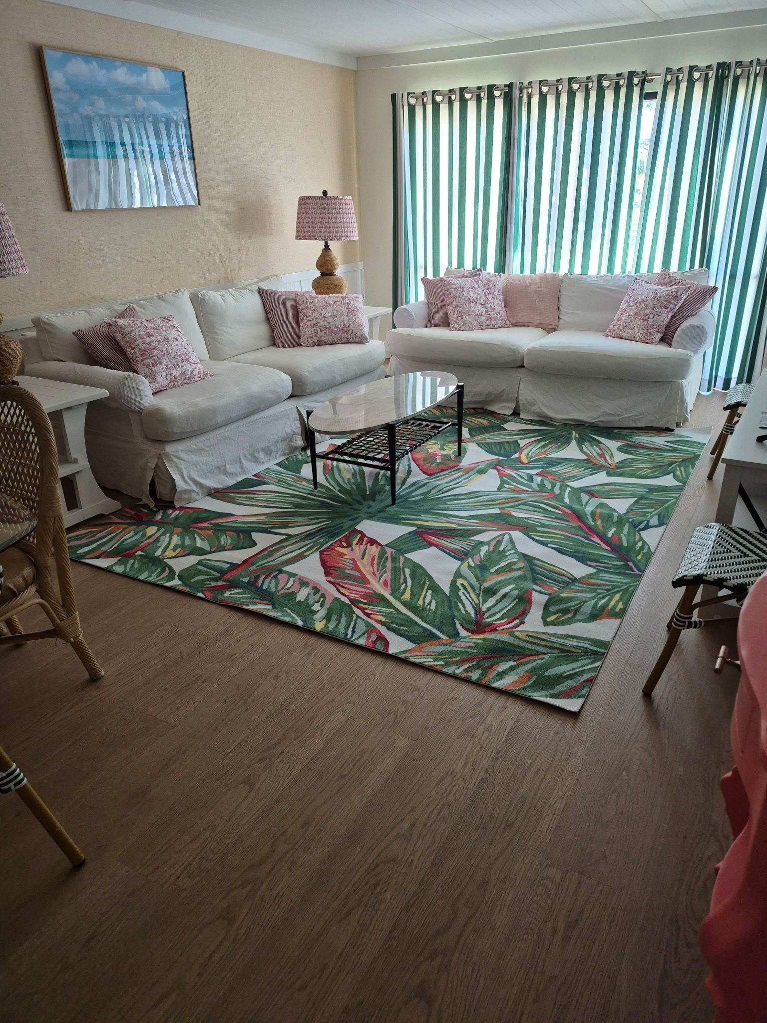 A living room with two white sofas, a coffee table, a patterned rug, and a lamp.