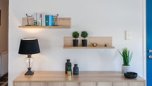 A wooden console table with a black lamp, two potted plants, and decorative items.