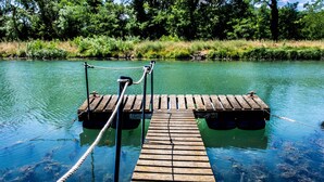 A wooden dock extending into a clear body of water, surrounded by lush greenery. - Cozy attic apartment (Charmes-sur-Rhône)