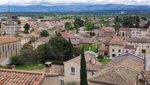 A town with historic buildings, a prominent church tower, and a mountainous backdrop. - Cozy attic apartment (Charmes-sur-Rhône)