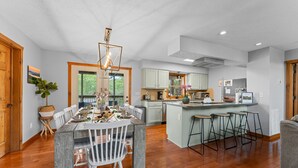 A spacious kitchen with a central island, wooden flooring, and a dining area with a table and chairs.