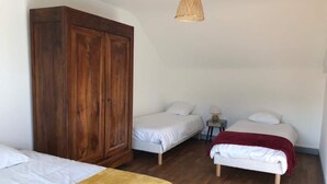 Une chambre avec deux lits, une armoire et un luminaire suspendu.