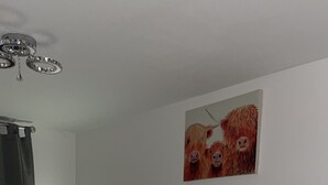 A bedroom with a bed, a desk with a mirror, and a painting on the wall. - Affordable luxury apartment (Stratford)