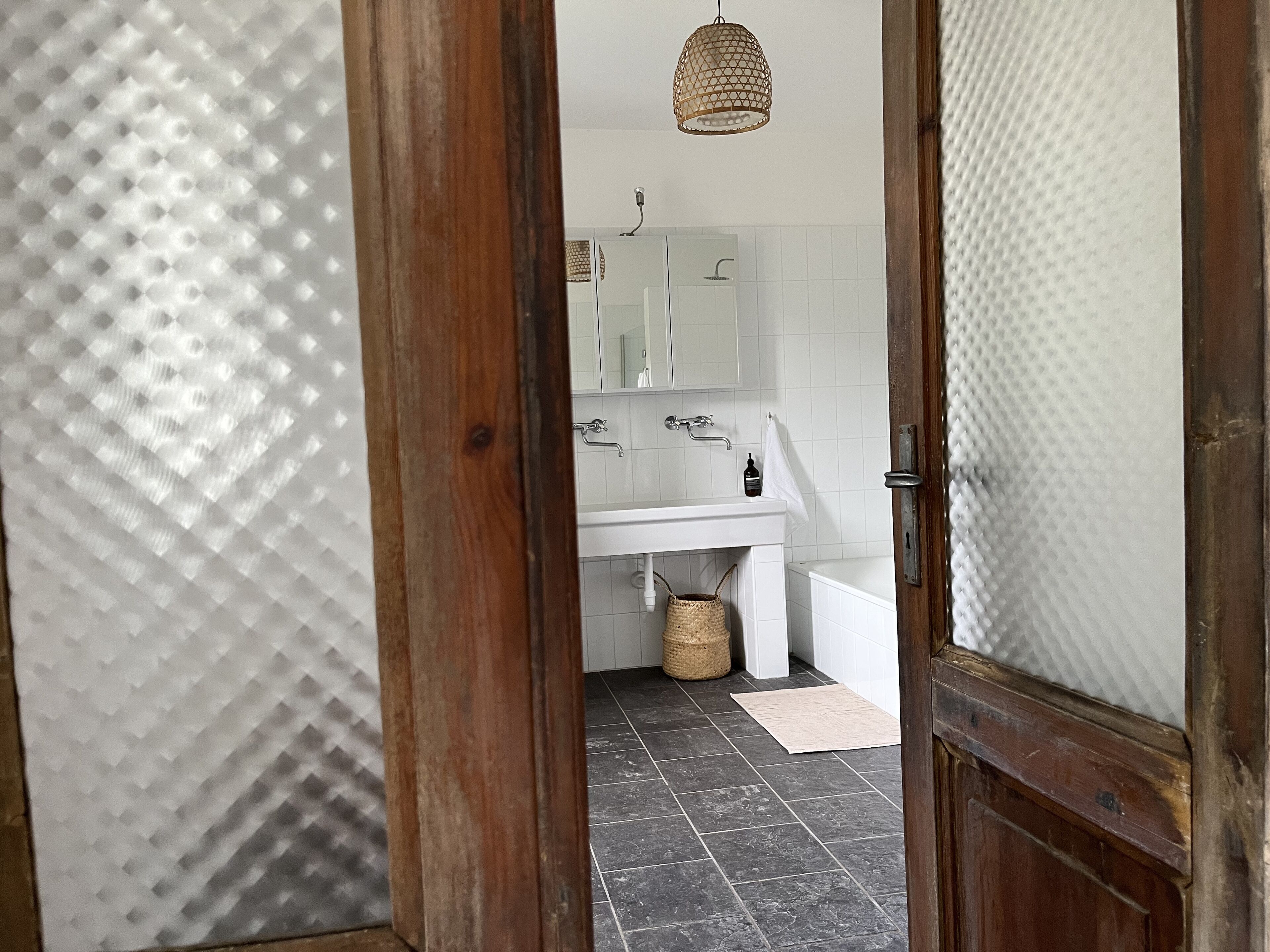 A bathroom with a white sink, mirror, and tiled floor.