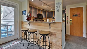 A kitchen with wooden cabinets, a microwave, and a bar area with stools. - Beautiful 3BR/3BA Fall Line Condo with Mountain Views, Hot Tub, Pool, Shuttle. G2A/B (Killington)