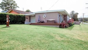 A single-story house with a front porch, a mailbox, and a small garden area.