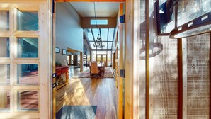 A spacious interior with a high ceiling, large windows, and a dining area with a chandelier. - Peaceful Setting | Fireplace | Aspen Skyview (Angel Fire)