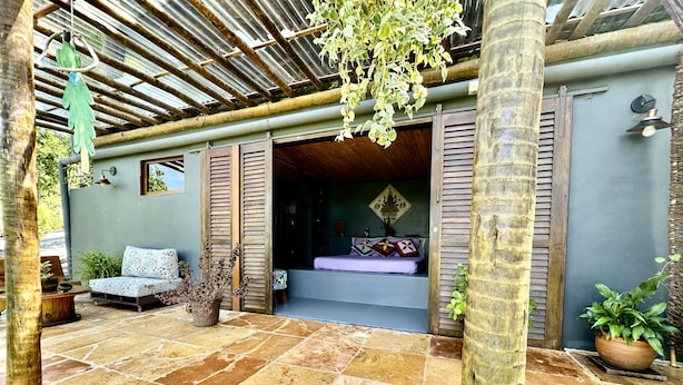 Un espacio al aire libre acogedor con suelo de piedra, mobiliario de madera y plantas en macetas.