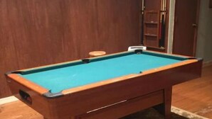 Un biliardo in una stanza con pavimento in legno e tappeto decorato.