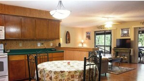 Una cucina con mobili in legno, un tavolo da pranzo con sedie e una televisione nella zona giorno.
