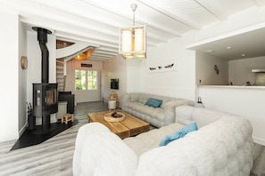 Un salon moderne avec une cheminée, un ensemble de canapés, une table basse en bois et un luminaire suspendu.