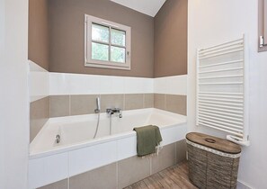 A modern bathroom with a bathtub, a window, and a towel rack.