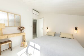 A bedroom with a bed, bedside tables, a mirror, and wall-mounted lights.