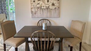 Uma sala de jantar com uma mesa de madeira escura, duas cadeiras estofadas e um jarro branco sobre a mesa.