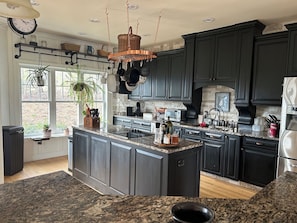 A modern kitchen with dark cabinetry, granite countertops, and a central island.