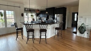 A modern kitchen with a large island, bar stools, and a view of the outdoors. - Spectacular long range views! 5 minutes from Franklin. Private w/paved driveway. (Franklin)