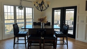 A dining area with a dark wooden table, four black upholstered chairs, a vase with flowers, and a chandelier. - Spectacular long range views! 5 minutes from Franklin. Private w/paved driveway. (Franklin)
