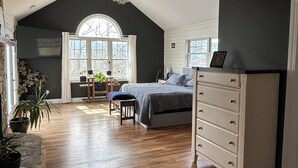 A spacious room with a large bed, a dresser, and a desk with a chair. There is a window with a view of trees and a door leading to another room. - Spectacular long range views! 5 minutes from Franklin. Private w/paved driveway. (Franklin)