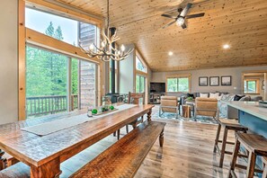 A spacious living area with a large wooden dining table, a ceiling fan, and a view of the outdoors.