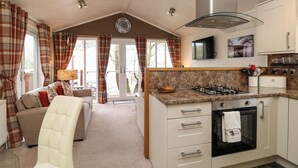 A modern kitchen with a gas stove, oven, and a TV mounted above the counter. - Shoreside Lodge (Windermere)