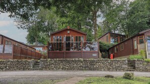 A wooden lodge with a stone wall entrance, a covered porch, and a sign reading "Shoreline Lodge". - Shoreside Lodge (Windermere)