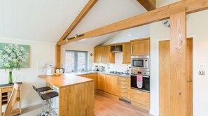 A kitchen with wooden cabinets, a central island, a microwave, and a sink. - Sheffield Pike Lodge (Windermere)