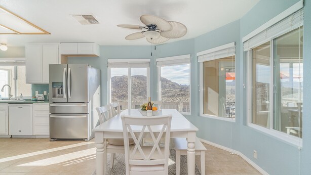A modern kitchen with white cabinets, stainless steel appliances, and a dining area with a white table and chairs.