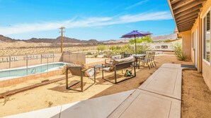 A pool area with lounge chairs, a table, and an umbrella.