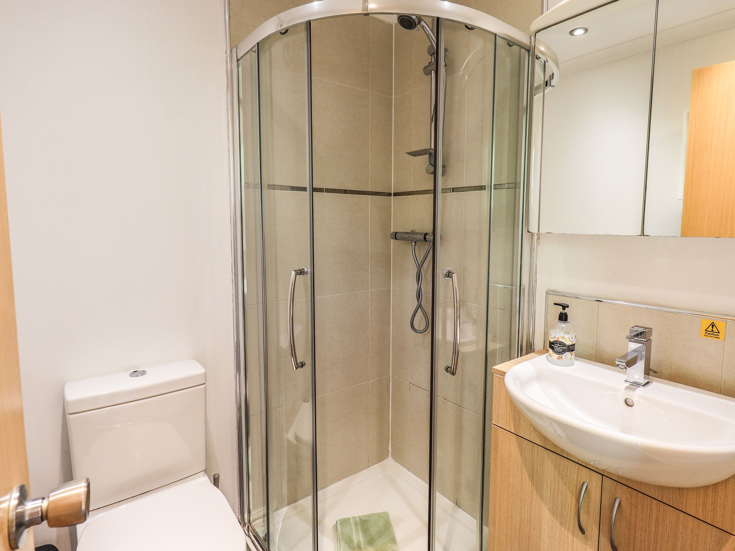 A modern bathroom with a glass-enclosed shower, a white sink, and a toilet.