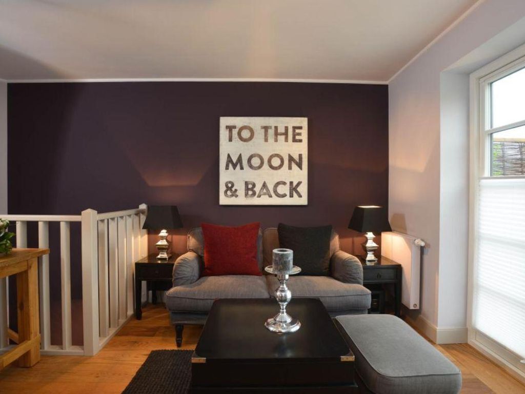 A cozy living room with a sofa, two side tables with lamps, a coffee table, and a decorative sign on the wall.