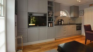 A modern kitchen with grey cabinets, a black countertop, and a window. - Villa Maybach, Whg. 5 Metropol - Villa Maybach (Sylt)