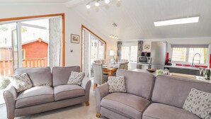 A spacious living area with two sofas, a dining table, and a kitchen area with a microwave and sink. - Limefitt Lodge (Windermere)