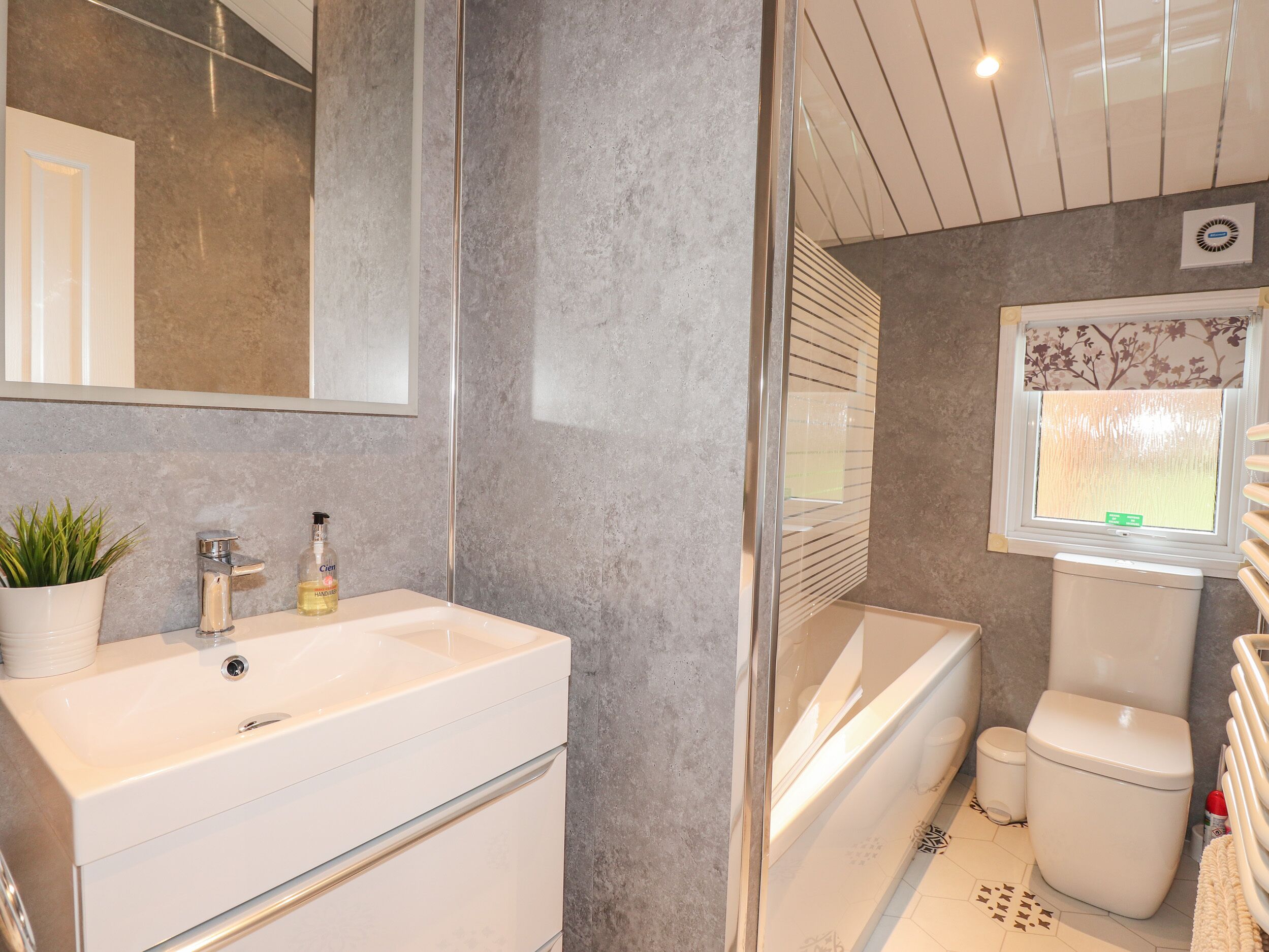 A bathroom with a white sink, mirror, and toilet.