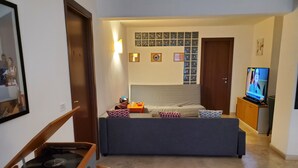 Ein Wohnzimmer mit einer Couch, einem Fernseher und einem Holzschrank mit Plattenspieler.