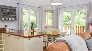 A cozy kitchen with a dining area, a wooden counter, and a view of greenery outside. - Ambleside Lodge (Windermere)