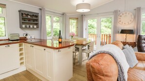 A modern kitchen with a central island, a dining area with a table and chairs, and a cozy living room with a sofa. - Ambleside Lodge (Windermere)