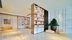 A modern interior with a large bookshelf, a reception desk, and a potted plant. - Ji Hotel (Suzhou)