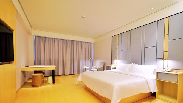 A modern hotel room with a large bed, bedside tables, a desk, and a chair. - Ji Hotel (Suzhou)