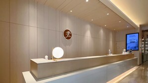 A hotel reception desk with a digital screen, a round mirror, and a sign with Chinese characters. - Ji Hotel (Suzhou)
