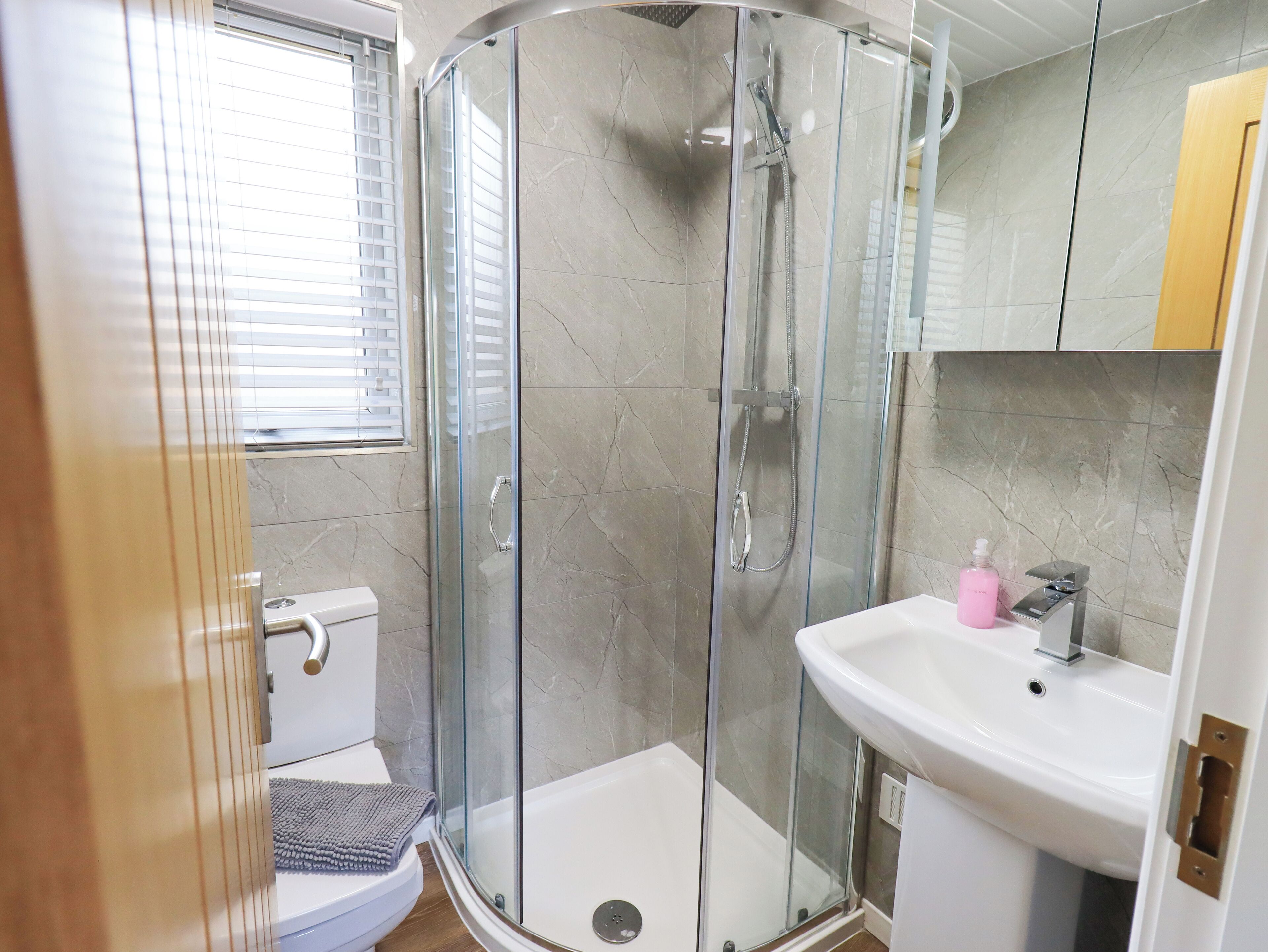 A modern bathroom with a glass-enclosed shower, a white sink, and a toilet.