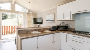 Una cocina moderna con gabinetes blancos, microondas integrado y estufa a gas.