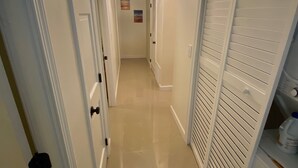 A hallway with white doors, a light fixture on the ceiling, and a tiled floor.
