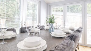 Comedor con mesa de madera dispuesta para cuatro personas, rodeado de sofás grises.