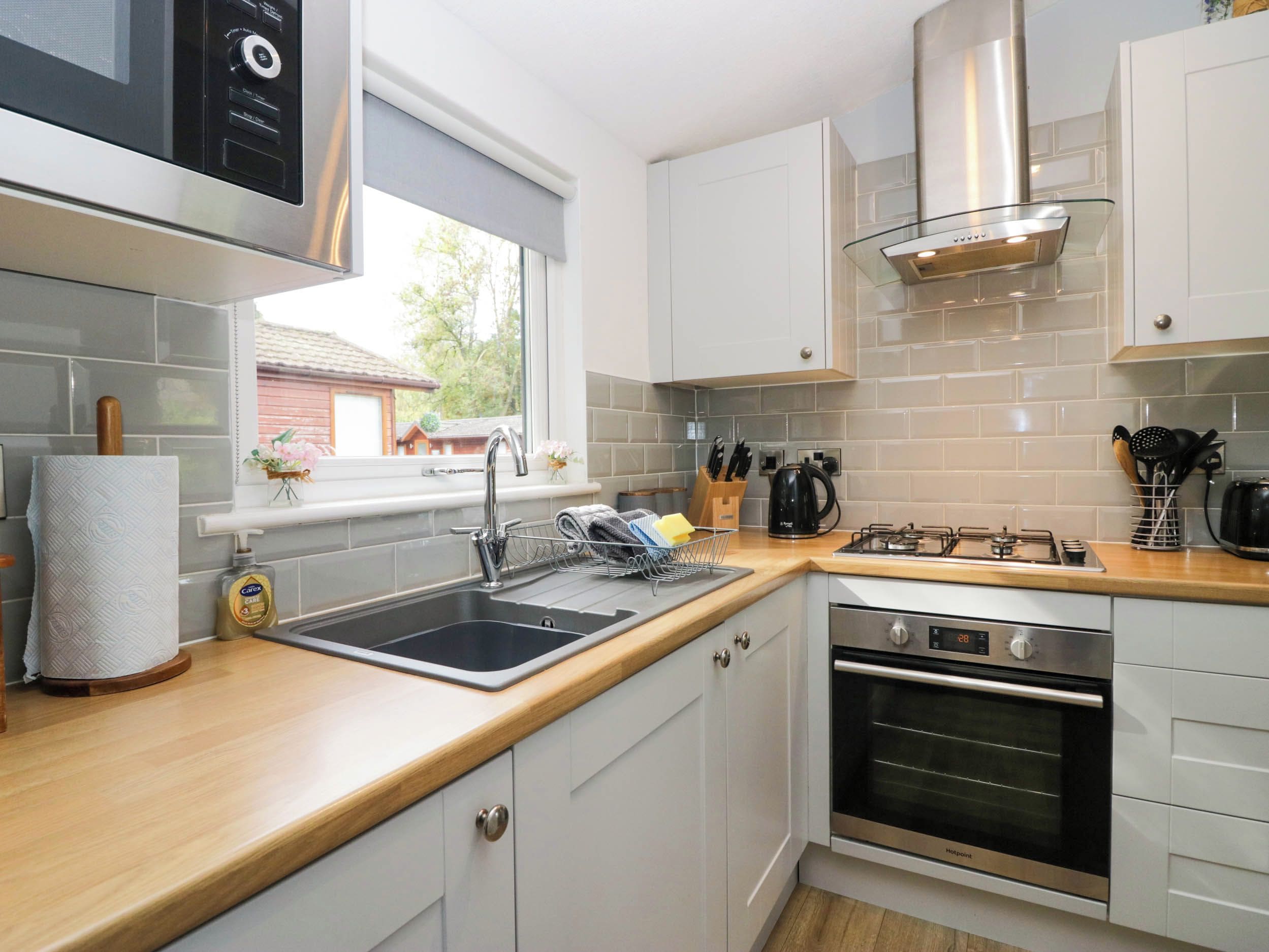 A modern kitchen with a stainless steel range hood, a built-in oven, and a window providing natural light.