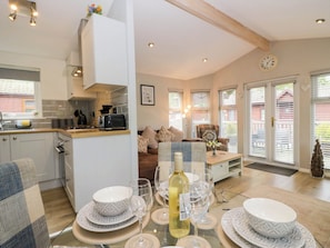 A modern kitchen with a dining area, a sofa, and a coffee table. - Badgers Hollow Lodge (Windermere)