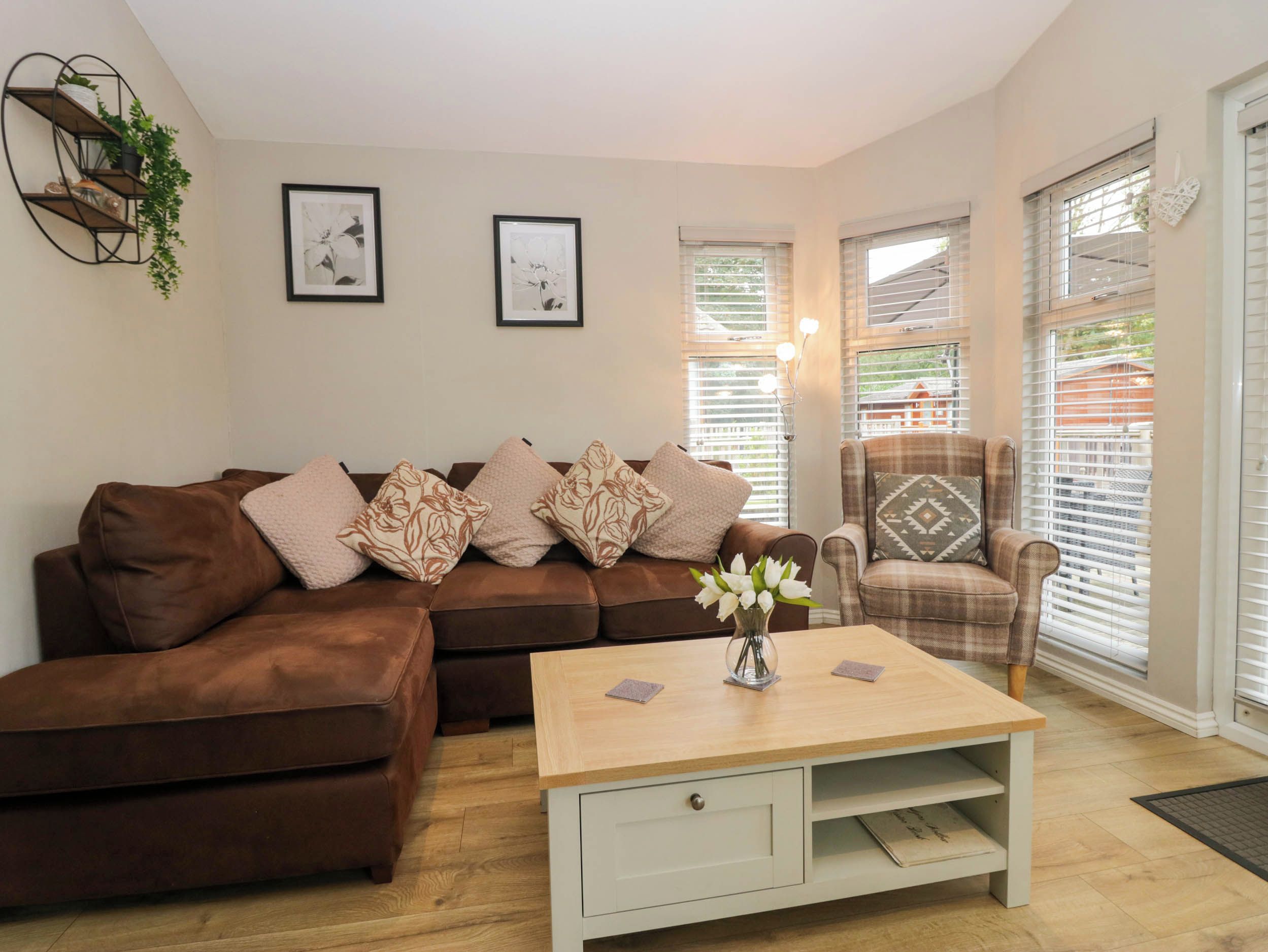 A living room with a brown sofa, a plaid armchair, a wooden coffee table, and two framed pictures on the wall.