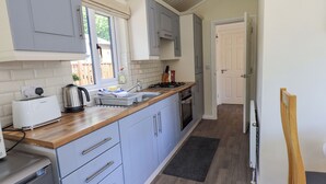 A modern kitchen with grey cabinets, a wooden countertop, and a built-in oven. - Robin View Lodge (Windermere)