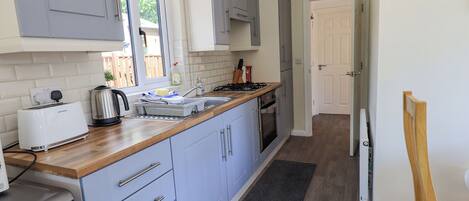 A modern kitchen with grey cabinets, a wooden countertop, and a built-in oven.