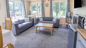 A cozy living room with two sofas, a coffee table, and a TV. - Robin View Lodge (Windermere)