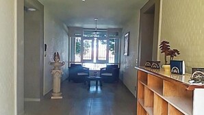 Um corredor com chão de azulejos, um ventilador de teto e vista para uma sala de jantar com mesa e cadeiras.